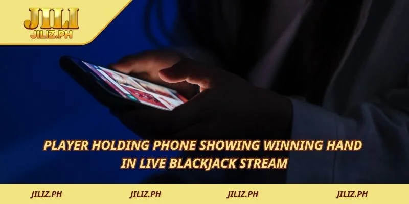 Player holding phone showing winning hand in live blackjack stream
